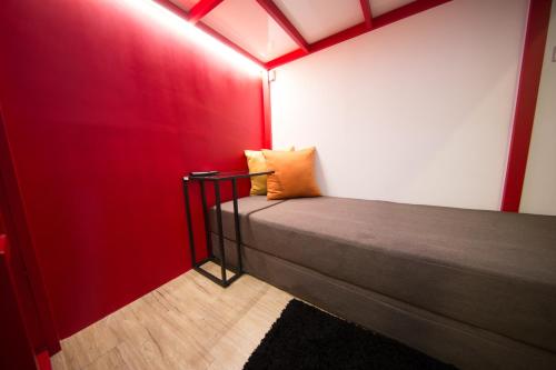 a room with a red wall with a bed in it at SleepBox Hostel in Taipei