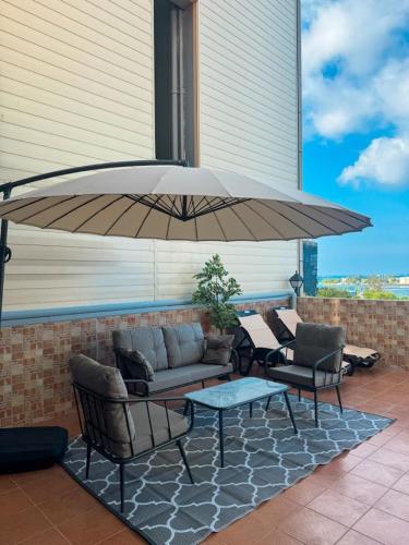 a patio with a couch and chairs under a large umbrella at Nalahost 2BR Seaview Terrace apartment in Male City