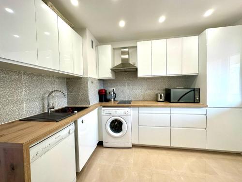 une cuisine avec des armoires blanches et une machine à laver dans l'établissement Mike by Terry's Homes, à Cannes