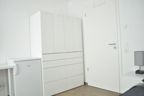 a white kitchen with white cupboards at B Home SLEEP & WORK in Burgrieden