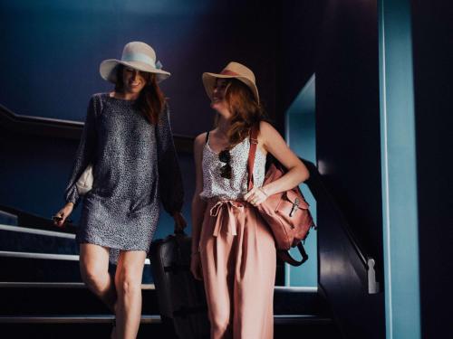 two women are walking down the stairs wearing hats at Hôtel Mercure Rochefort La Corderie Royale in Rochefort