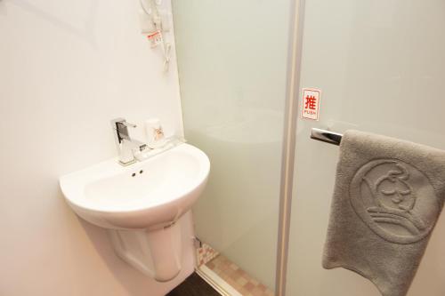 a bathroom with a toilet and a sink and a towel at SleepBox Hostel in Taipei