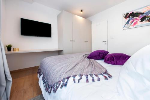 a bedroom with a bed with purple pillows and a tv at Apartments with private jacuzzi Garbin 1 and Garbin 2 in Rovinj