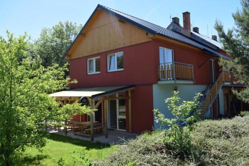 a red house with a porch and a balcony at Penzion Slunečno in Dobšín