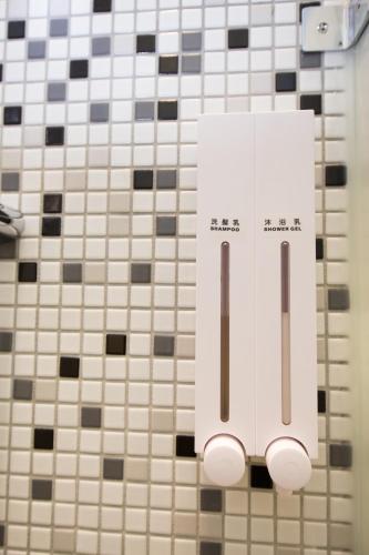 a towel dispenser on a tiled bathroom wall at SleepBox Hostel in Taipei