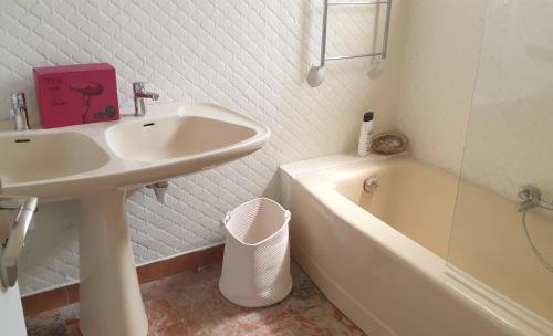 une salle de bain blanche avec un lavabo et une baignoire dans l'établissement villapiscineXL, à Montady