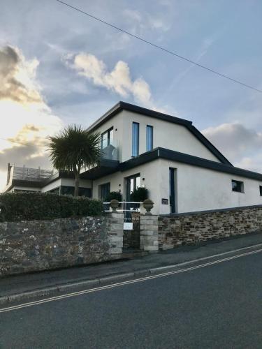 a white house with a palm tree in front of it at Mevagissey Boutique Flatlet with sea and countryside views in Mevagissey