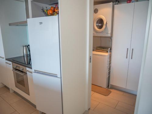 a kitchen with white cabinets and a refrigerator at Villa 3 Luxe Coastal Escape in Cable Bay