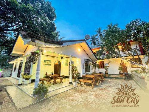 a patio of a house with wooden tables and benches at SunCity Airport Transit Stay in Minuwangoda