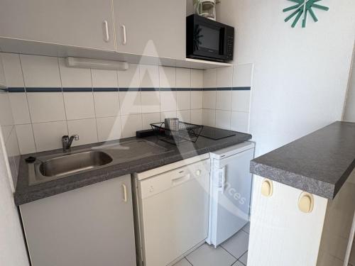 une petite cuisine avec un évier et un micro-ondes dans l'établissement 1 CHAMBRE, VUE MER, ACCES DIRECT PLAGE, à Sète