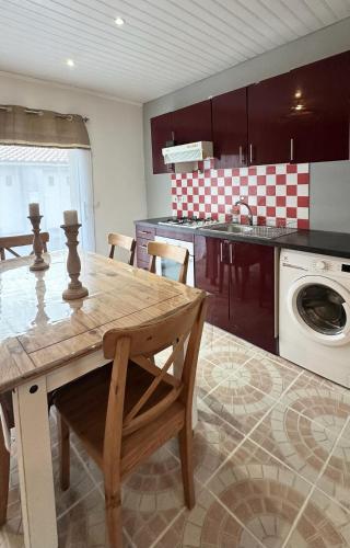 une cuisine avec une table en bois et un lave-linge dans l'établissement Le Nid du Lac, à La Chevrolière