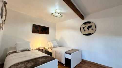 - une chambre avec 2 lits et une horloge murale dans l'établissement Le Nid du Lac, à La Chevrolière