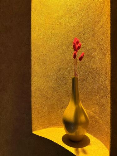 a yellow vase with a red flower in it at The Yalı Konak Hotel İzmir in Izmir