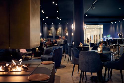a restaurant with tables and chairs and a fireplace at Van der Valk Hotel Amsterdam - Amstel in Amsterdam