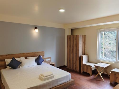 a bedroom with a bed and a chair and a window at Lamahatta Clouds Hotel & Restaurant in Takdāh