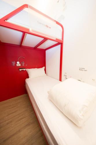 two beds in a room with a red wall at SleepBox Hostel in Taipei