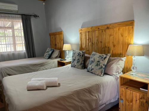 a bedroom with two beds with towels on the bed at Wooden Door Guesthouse in Brits
