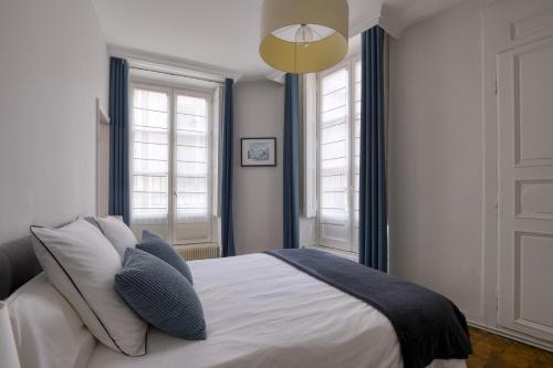 a bedroom with a bed and two windows at Appartement Saint Jean in Lyon
