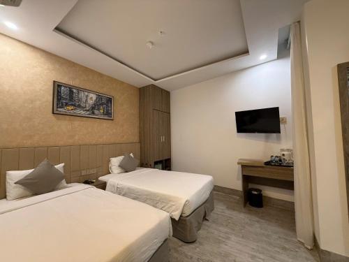 ニャチャンにあるAngel Hotelのベッド2台とテレビがあるホテルの部屋