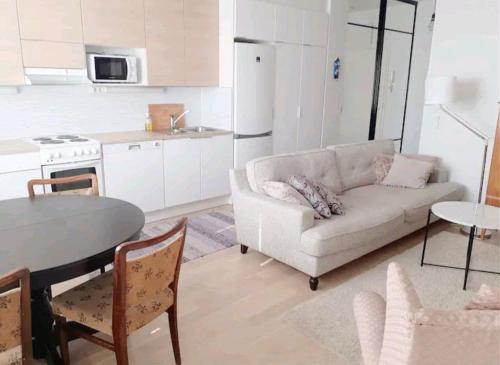 a living room with a couch and a table and a kitchen at Stylish city center home with sauna in Rovaniemi