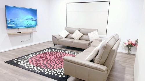 a living room with a couch and a tv at Elegant 5 Bed Brand New Spacious House in Clyde