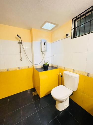 a yellow bathroom with a toilet and a shower at Gee Hills in Weligama