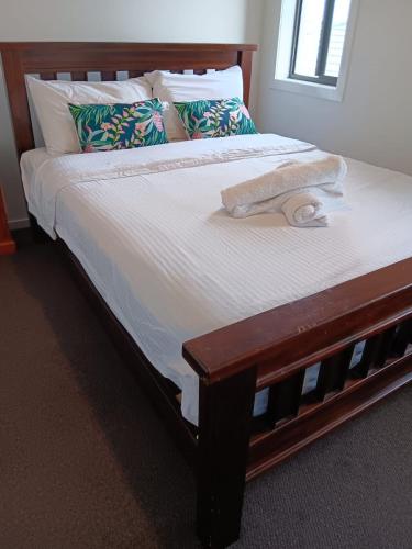 a bed with a wooden bed frame with a towel on it at Elegant 5 Bed Brand New Spacious House in Clyde