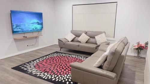 a living room with a couch and a flat screen tv at Elegant 5 Bed Brand New Spacious House in Clyde