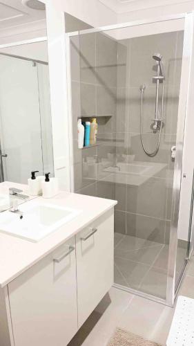 a white bathroom with a shower and a sink at Elegant 5 Bed Brand New Spacious House in Clyde