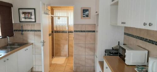 a small kitchen with a sink and a shower at Little Gem in Plettenberg Bay