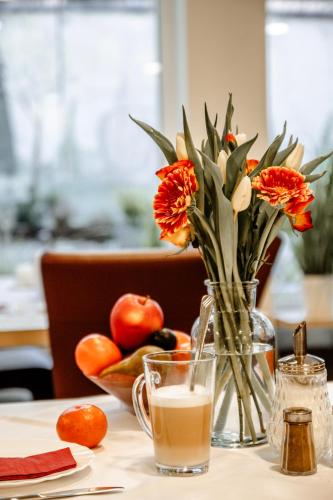 una mesa con un jarrón de flores y un vaso de leche en Hotel Central eGbR, en Würzburg
