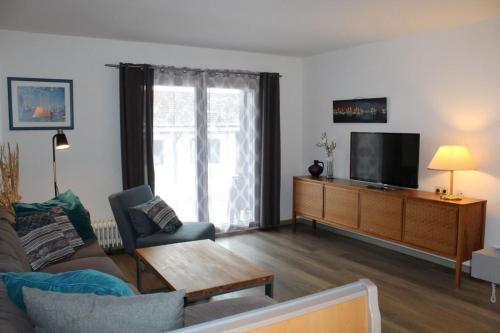 un salon avec un canapé et une télévision dans l'établissement Ferienhaus Nr 33, Kategorie Komfort, Feriendorf Hochbergle, Allgäu, à Lechbruck am See