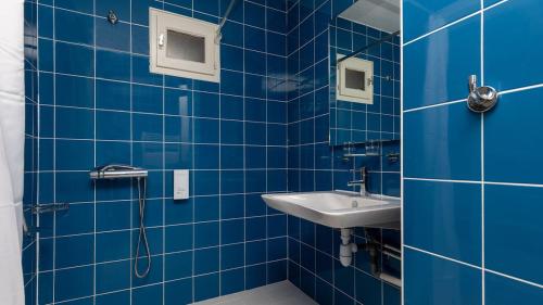 une salle de bain carrelée bleue avec un lavabo et une douche dans l'établissement Villages Clubs du Soleil - SOUSTONS, à Soustons