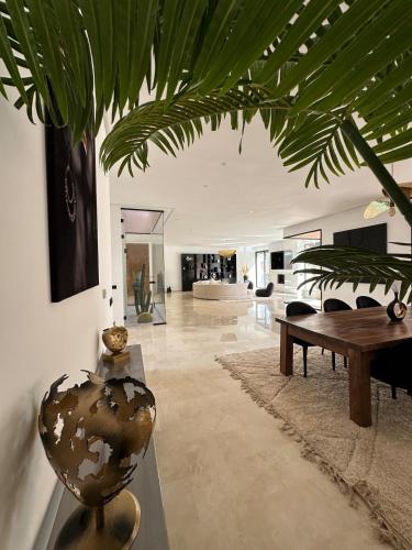 a living room with a table and a plant at Villa de standing piscine à débordement à 15 min de Marrakech in Ourika