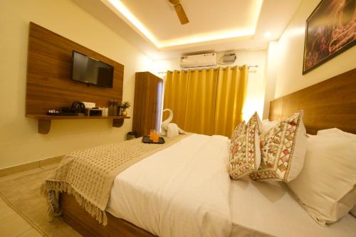 a bedroom with a bed with a television on the wall at Perfectstayz Value Forest Valley Rishikesh in Rishīkesh