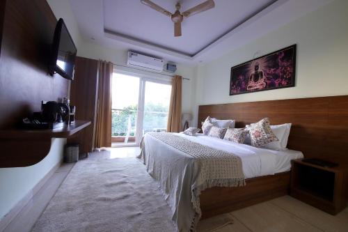 a bedroom with a large bed and a window at Perfectstayz Value Forest Valley Rishikesh in Rishīkesh