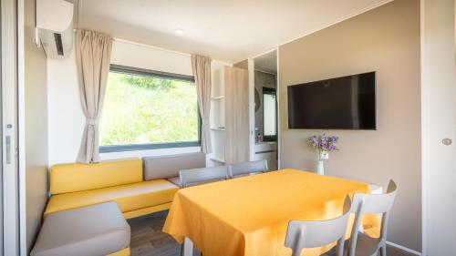 a living room with a yellow couch and a table at Agricamping Ai Prati in Lazise