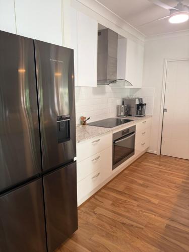 a kitchen with a stainless steel refrigerator and white cabinets at Tranquil Retreat - Your Own Room in a Peaceful Modern Shared House in Warner Lakes in Lawnton
