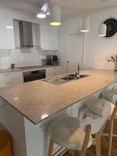 a kitchen with a counter with chairs and a sink at Tranquil Retreat - Your Own Room in a Peaceful Modern Shared House in Warner Lakes in Lawnton