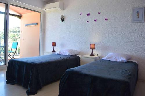 - 2 lits dans une chambre avec des papillons violets sur le mur dans l'établissement Appart 3 pièces 6 couchages BANYULS SUR MER BN190-002, à Banyuls-sur-Mer