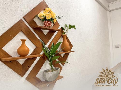 a wooden shelf with vases and flowers on a wall at SunCity Airport Transit Stay in Minuwangoda