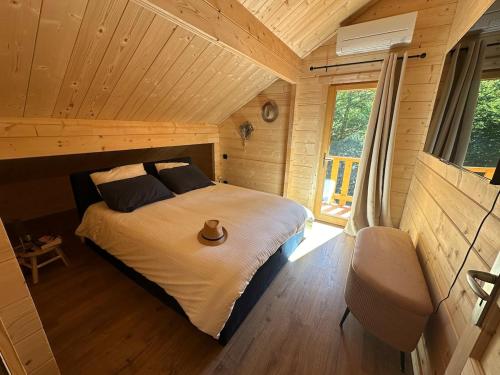 une chambre avec un lit dans une cabane en rondins dans l'établissement Chalet en fôret - 15 personnes, à Dourbies