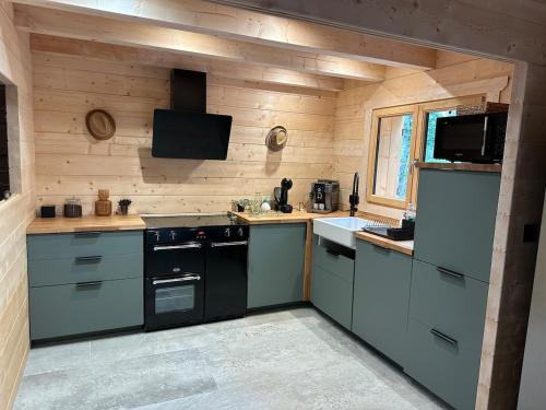 une cuisine avec une cuisinière et un évier dans l'établissement Chalet en fôret - 15 personnes, à Dourbies