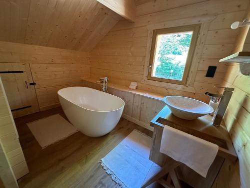 La salle de bains est pourvue d'une grande baignoire et d'un lavabo. dans l'établissement Chalet en fôret - 15 personnes, à Dourbies