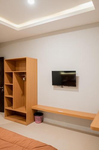 a living room with a tv on a wall and a shelf at De Luna Guest House in Kuripan