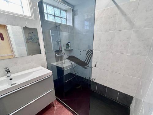 a bathroom with a sink and a glass shower at Le Boyard - En plein coeur de ville avec vue sur l'Océan in Fouras