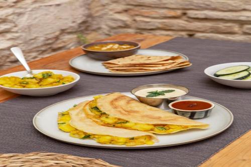 a table with plates of food on a table at Hotel Supreme - 700M From Vasco Da Gama Railway Station in Marmagao