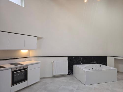 a kitchen with white cabinets and a bath tub at Aqua Loft Suite exécutive & élégante Quartier Européen Bruxelles in Brussels