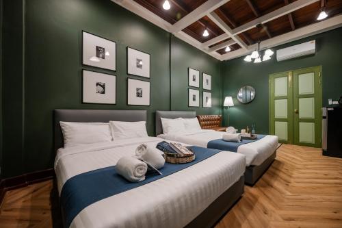 two beds in a room with green walls at Arun Sa Wad - Yaowarat 27 in Bangkok