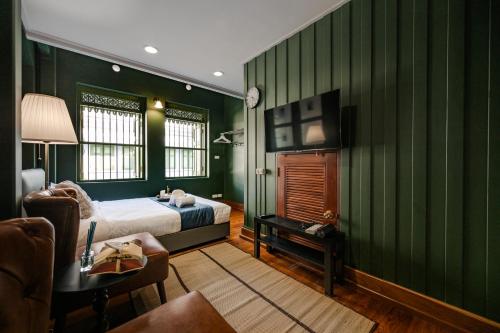 a bedroom with green walls and a bed and a tv at Arun Sa Wad - Yaowarat 27 in Bangkok